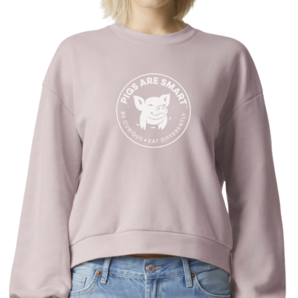 Person wearing the Premium ReFlex Crewneck in blush pink with Pigs Are Smart logo on front.